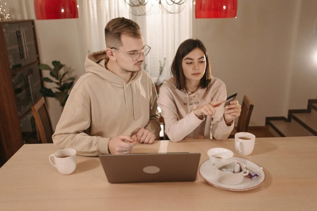 Person looking stressed at a kitchen table surrounded by online shopping boxes and receipts