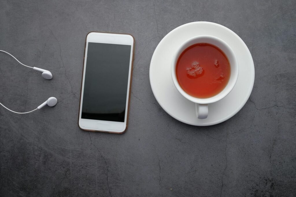 Phone face down on a table next to a cup of tea