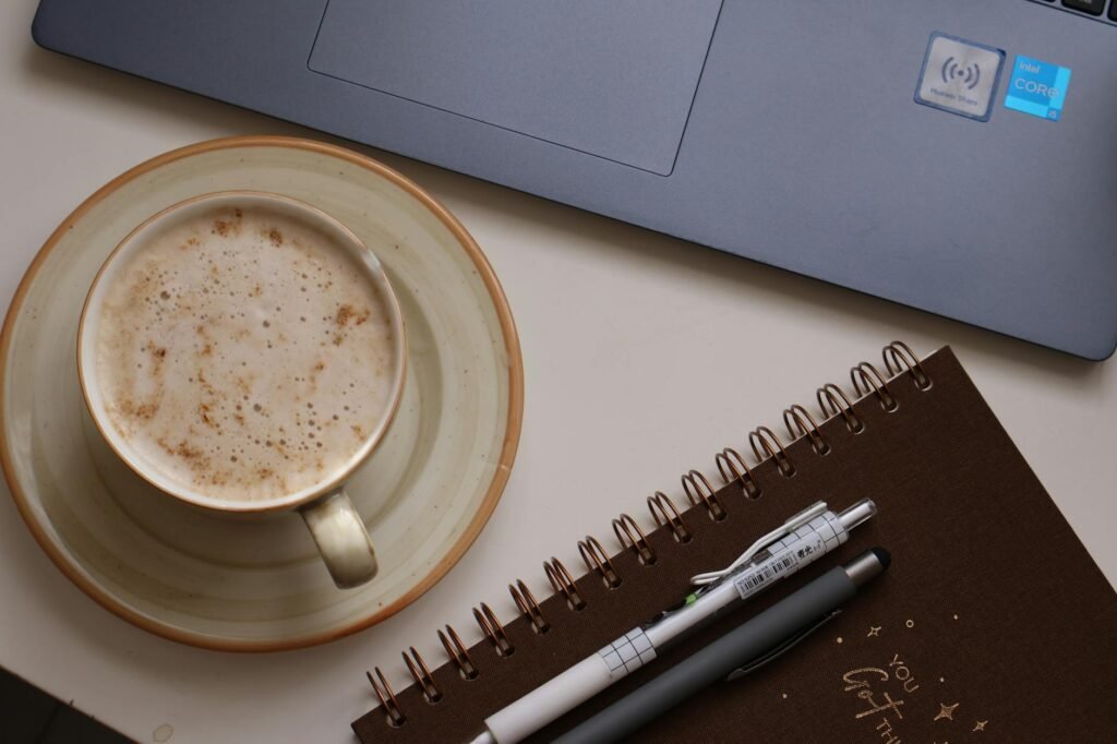 A simple desk setup for a weekly budget review with a notebook, pen, and laptop.
