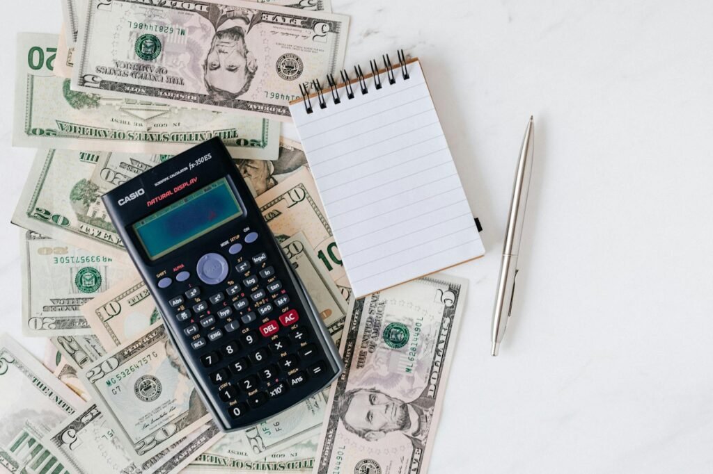 A desk with a notebook, calculator, and bank statements for budget planning