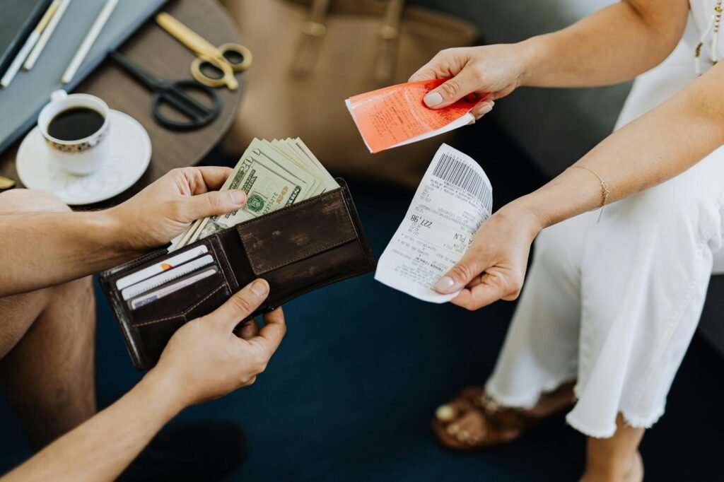 Hands sorting receipts beside a spending tracker sheet