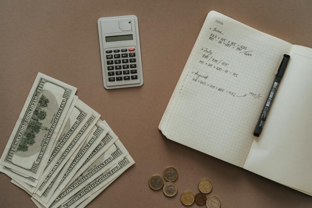 A desk with household bills, a notebook, and a calculator set up for a weekly money review