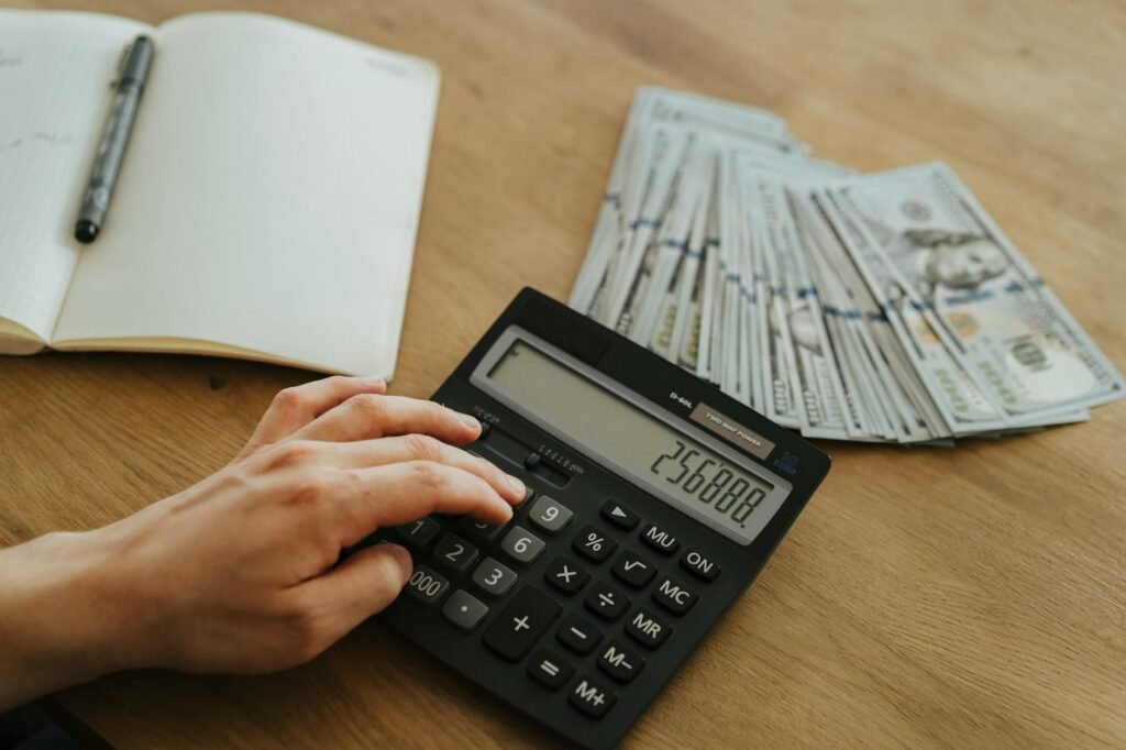 Printed bank statements, a calculator, and a notebook laid out on a desk for a budget review