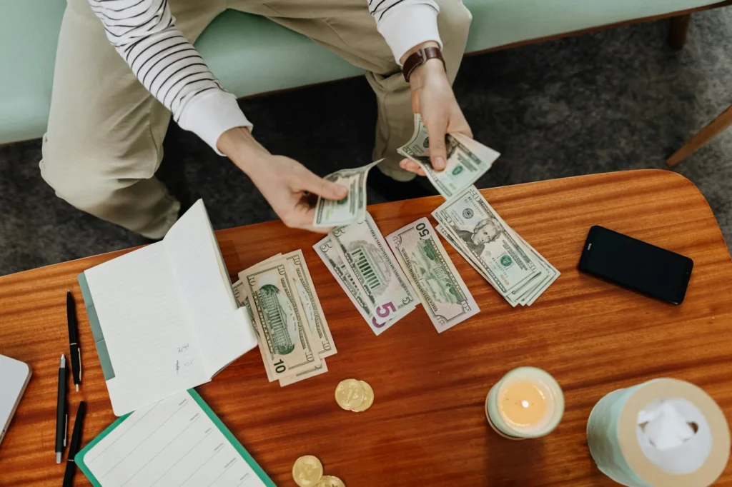 Person using a banking app next to a notebook labeled savings