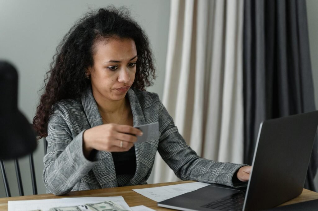 Someone reviewing monthly charges on a laptop with paper bills beside them.
