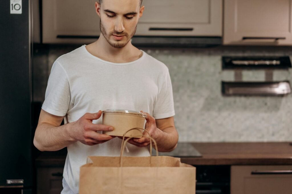 Meal prep containers next to a grocery list on a kitchen counter