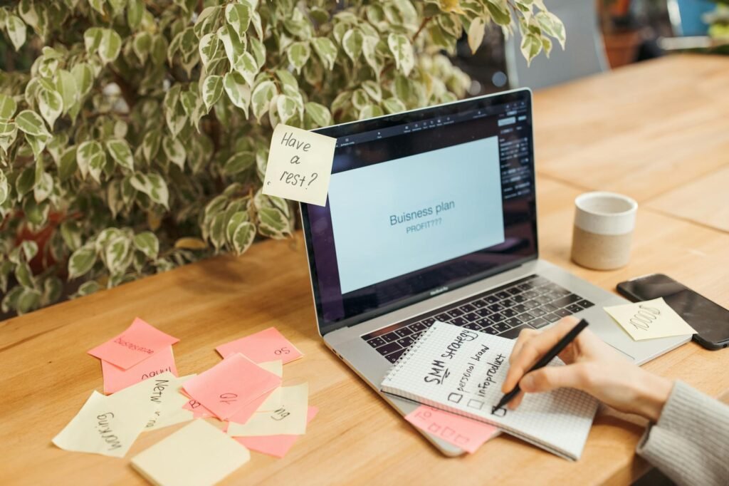 Notebook with a monthly budget checklist on a desk next to a laptop