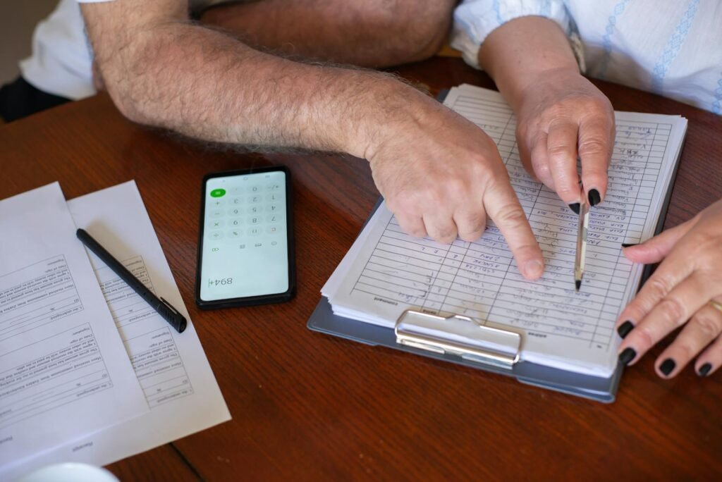 Hands reviewing bills with a calculator on a table