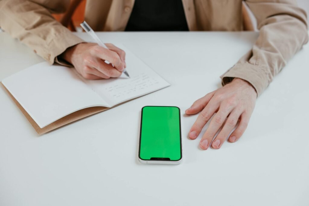 Someone taking notes in a notebook while on a phone call