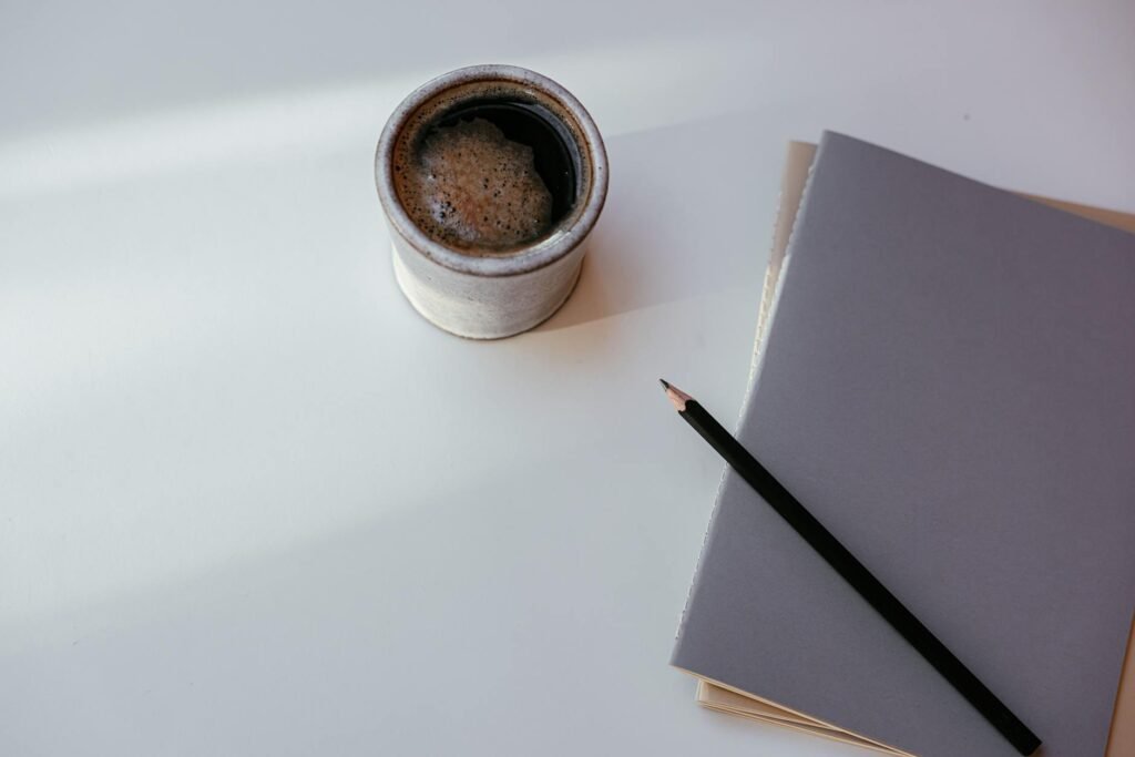 Budget notebook and pen on a desk next to a cup of coffee