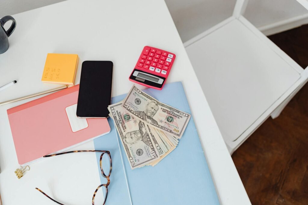 Household bills, calculator, and notebook laid out on a table for a budget review