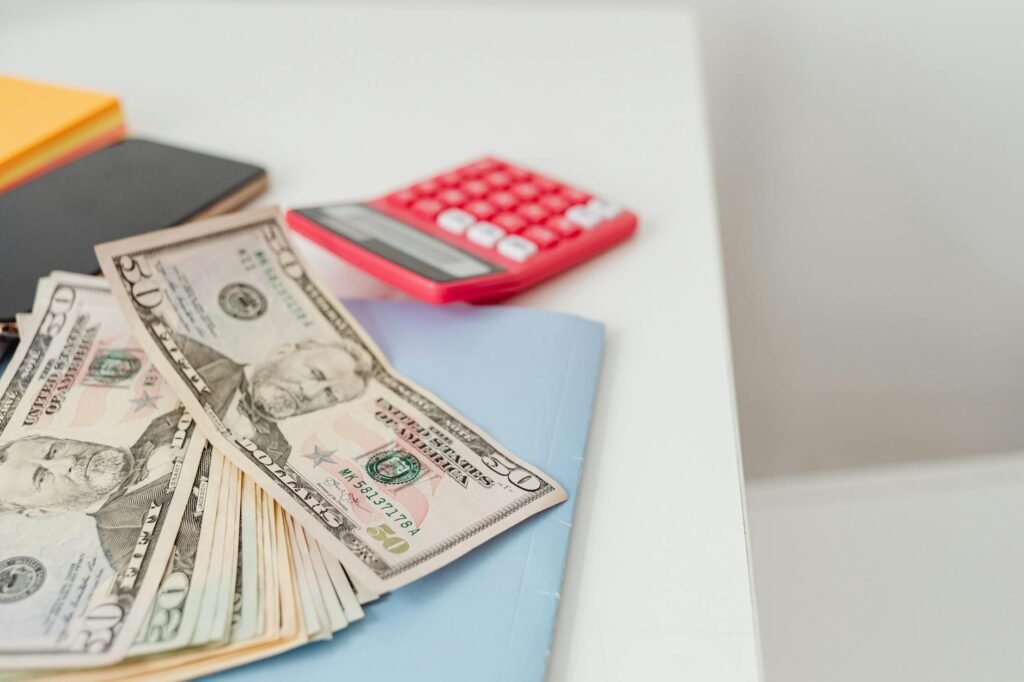 A home budget planning setup with bank statements, a calculator, and a notebook on a kitchen table.