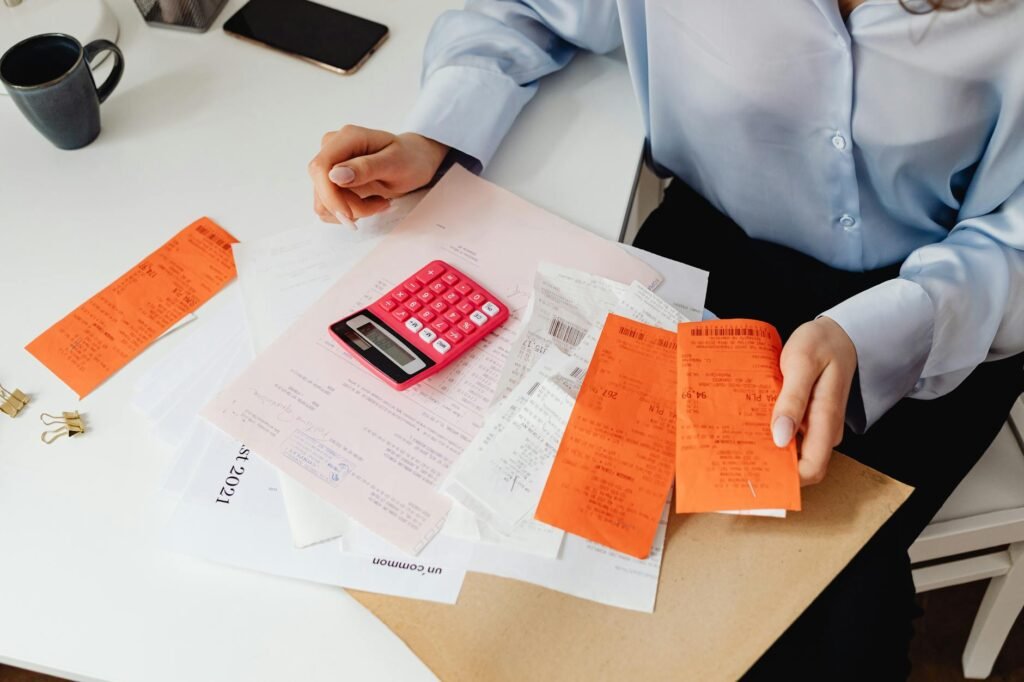 Hands reviewing bills and statements with a calculator during a monthly reset