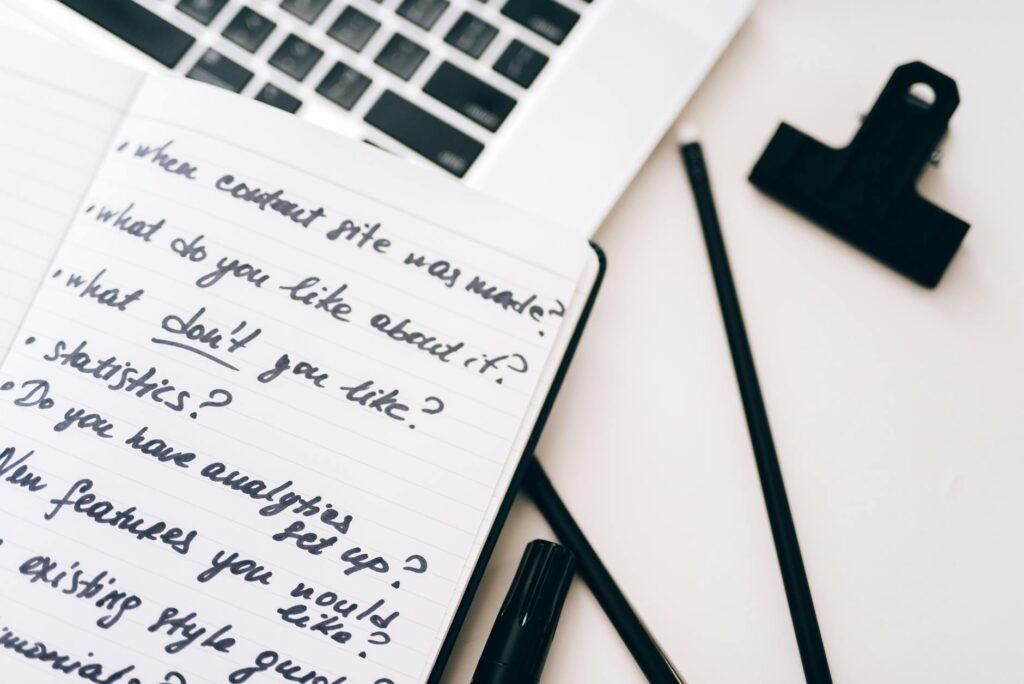 Laptop on a desk next to a handwritten pros and cons list
