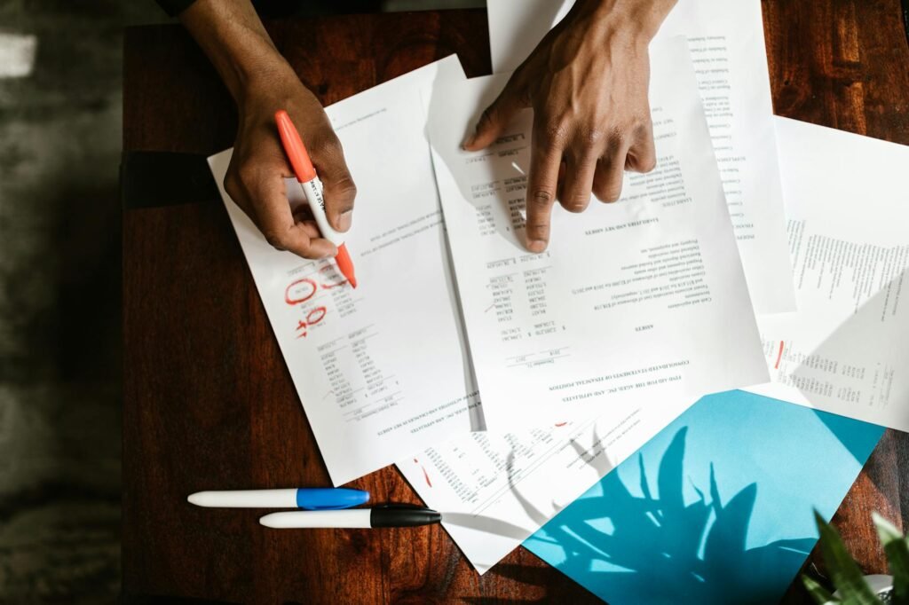 Hands highlighting transactions on a bank statement at a desk