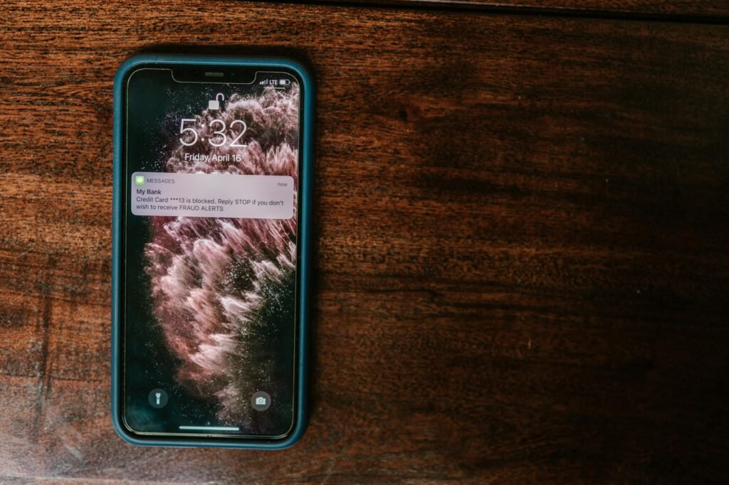 A phone displaying a low-balance alert next to a debit card