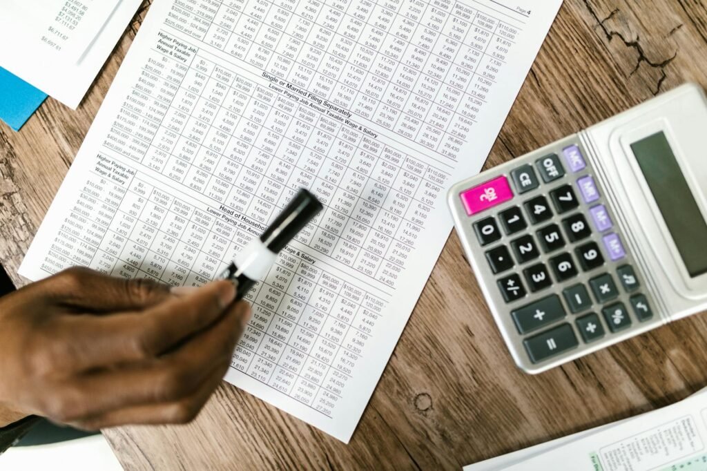 Calculator, notebook, and household bills spread across a table during a budget review