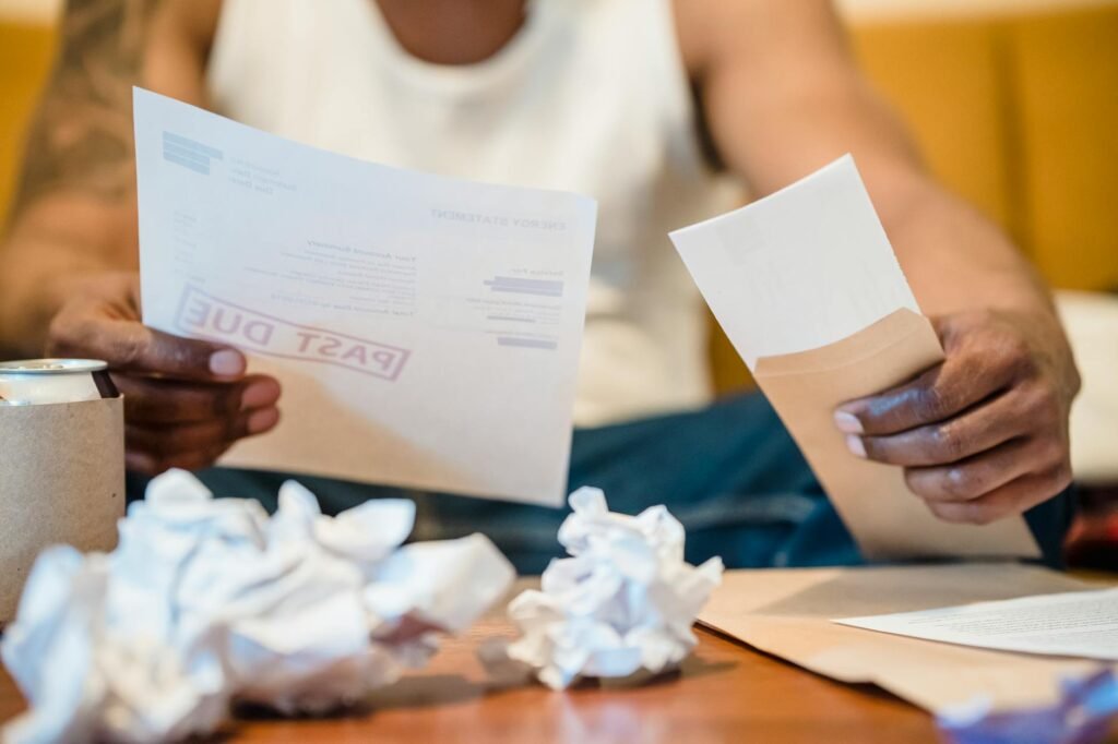 Hands sorting household bills into envelopes on a table