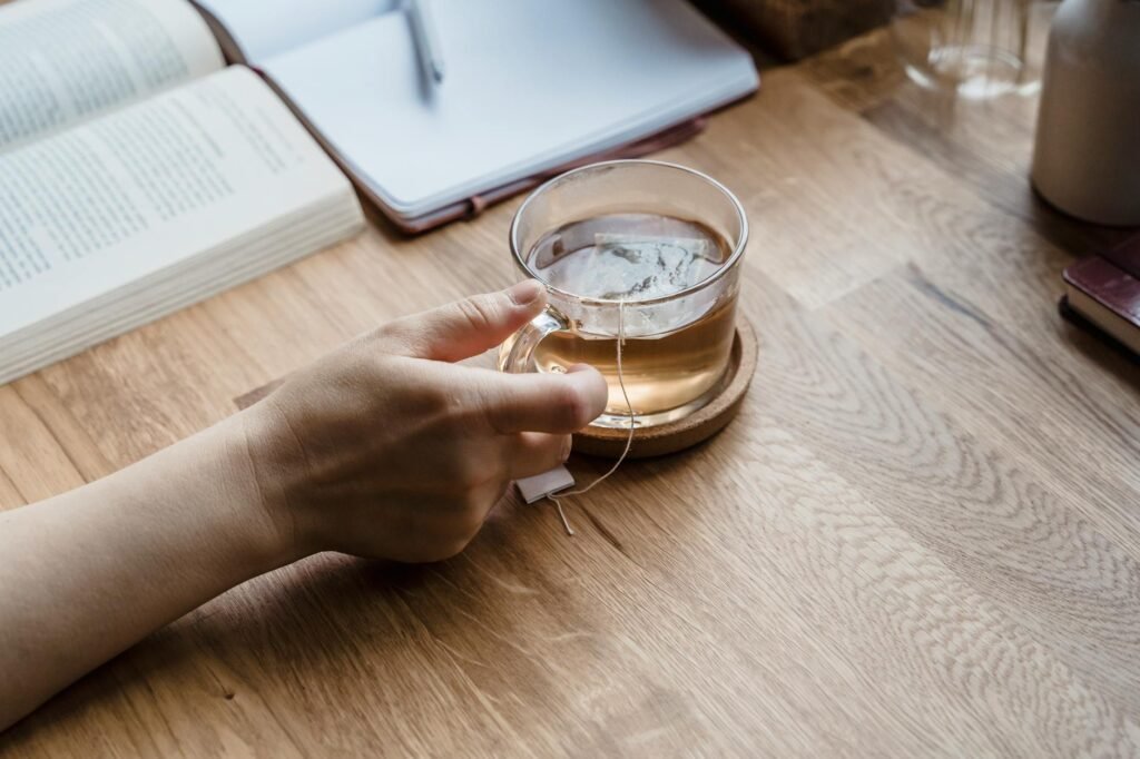 Phone face down next to a book and tea as a replacement for late-night scrolling