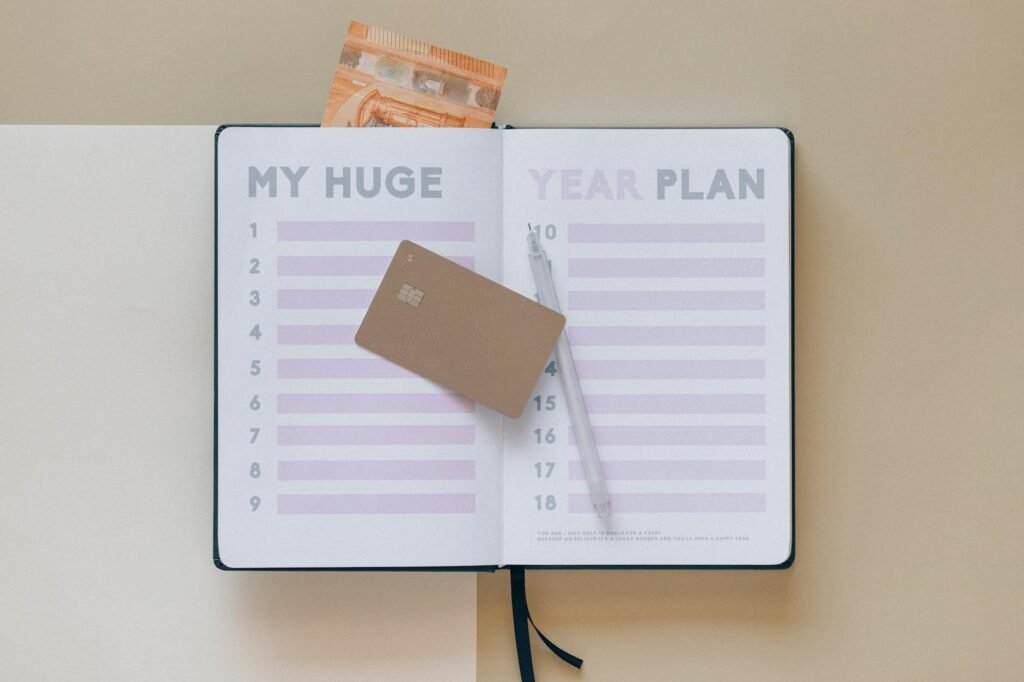 Notebook with savings goals next to a calendar and pen