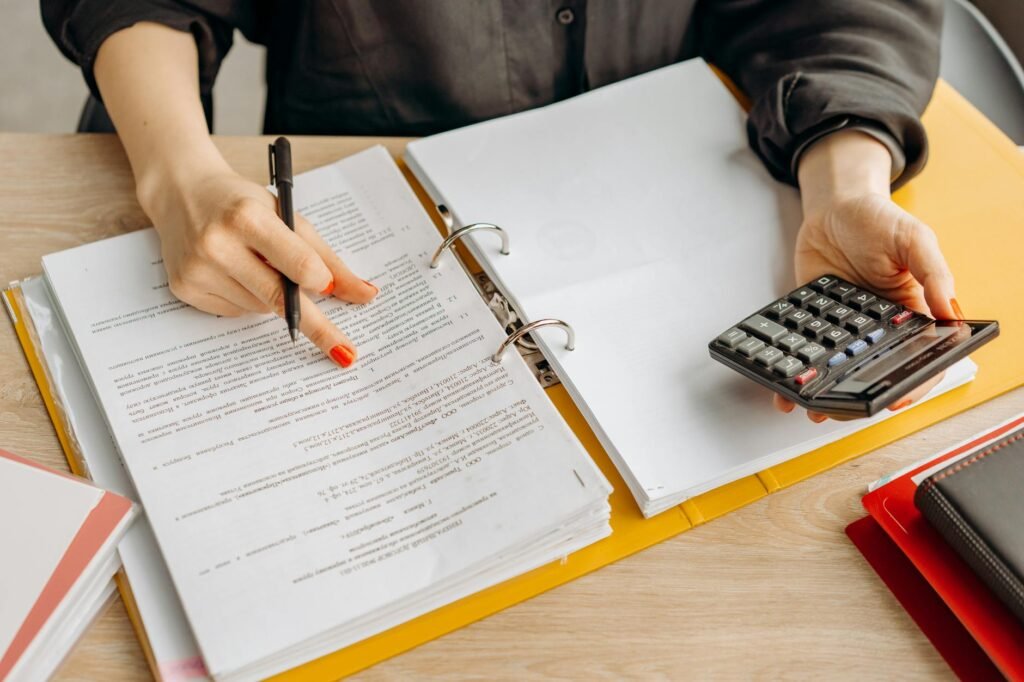 Hands holding a paystub next to a calculator on a table