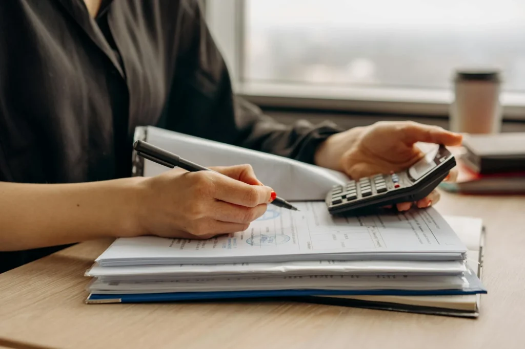 Person reviewing a bank statement at a desk with a calculator
