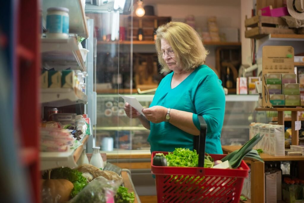 A grocery list next to vegetables on a kitchen counter