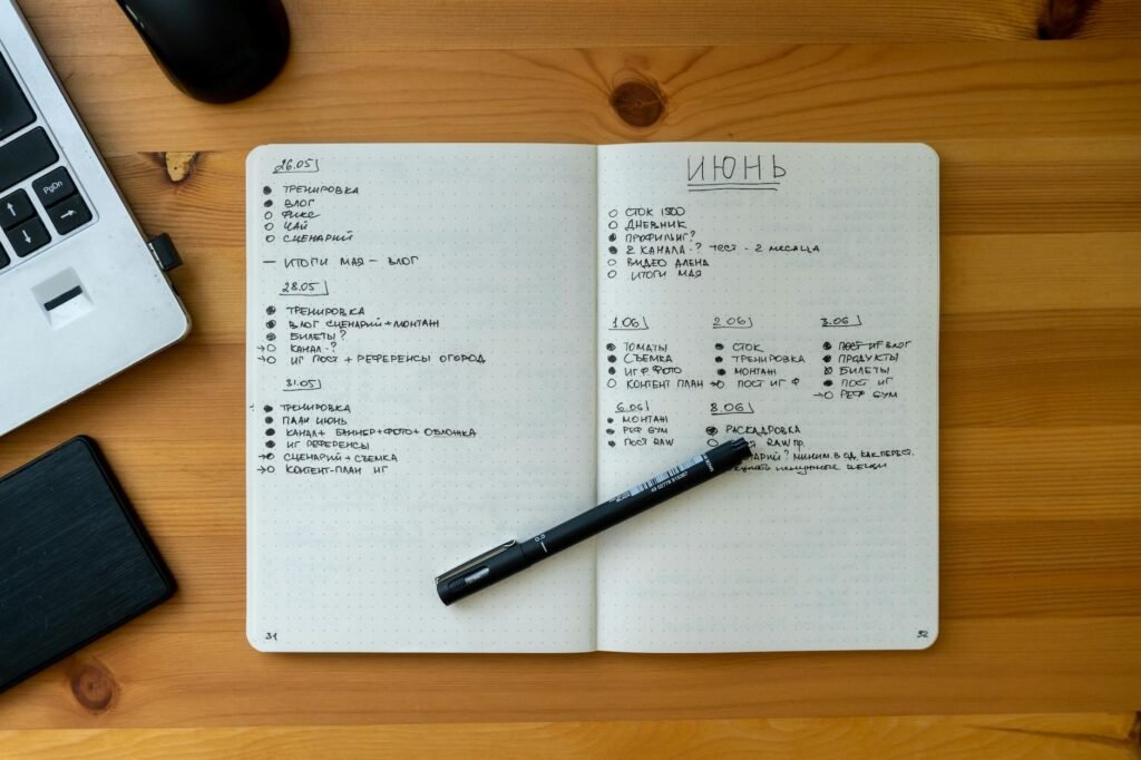 Notebook open on a desk with a simple spending tracker and pen