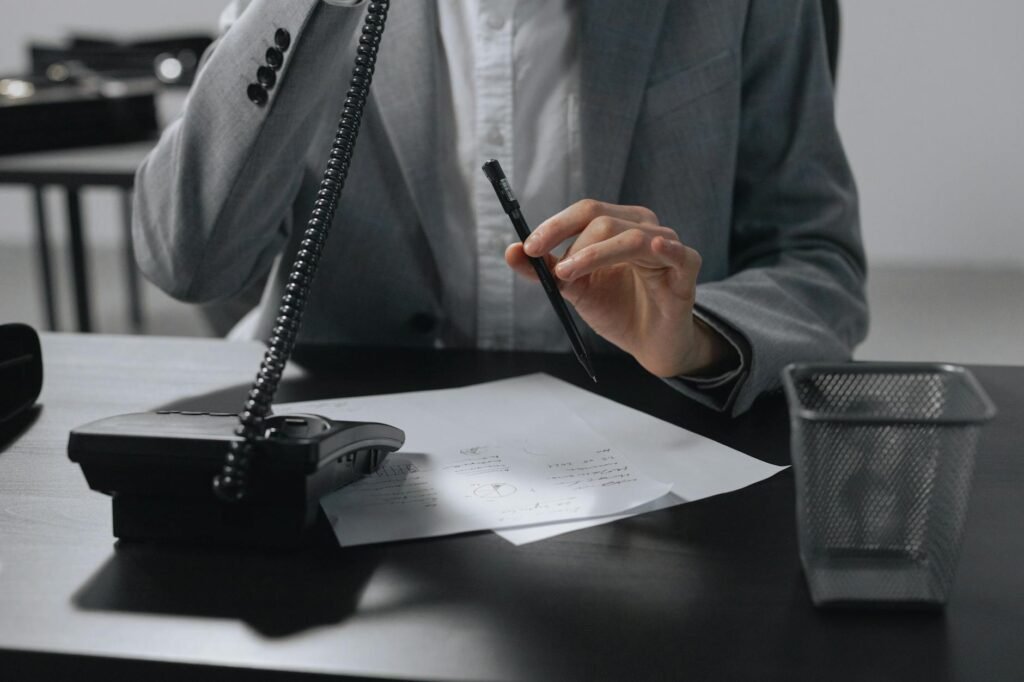 Hands holding a phone next to notes for calling a creditor