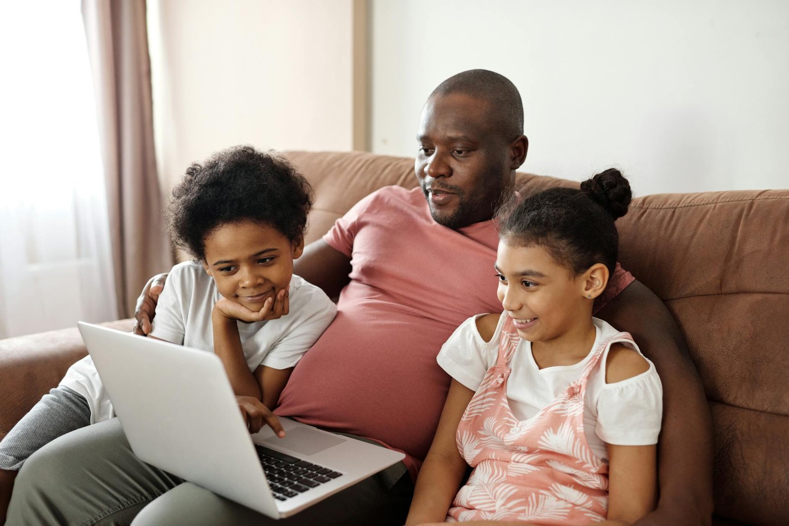 Father and children enjoying time together watching a laptop indoors.