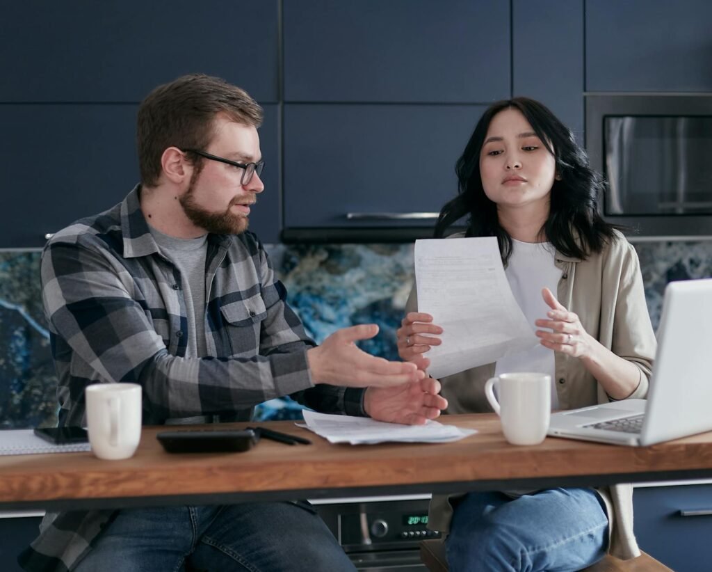 Person reviewing personal finances at a table with a laptop and bills