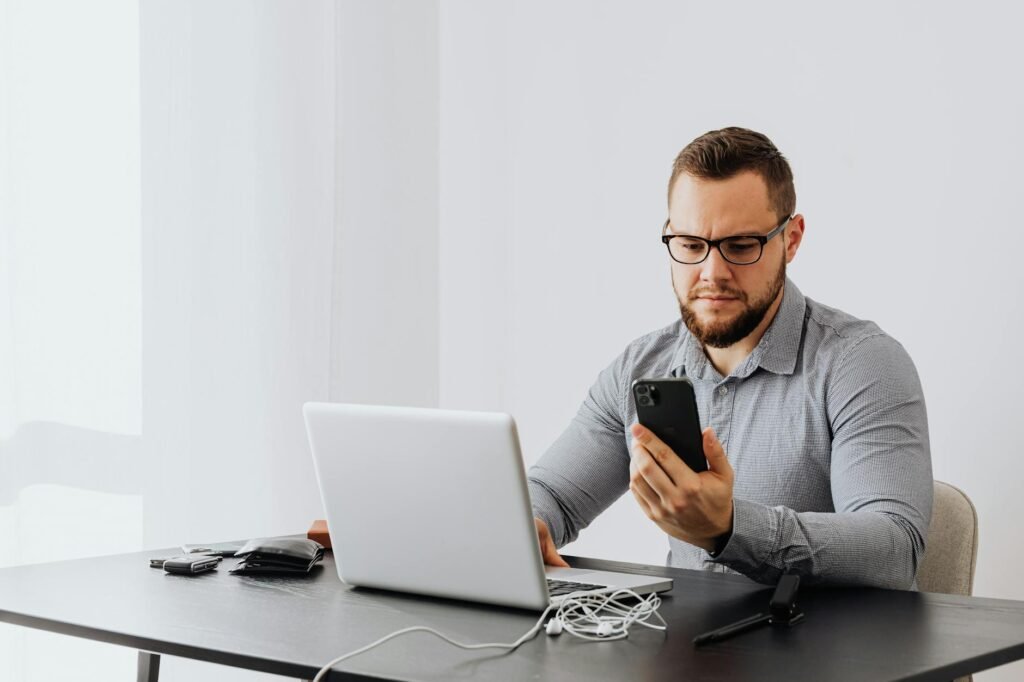 Professional man working at desk with laptop and smartphone, indoors.